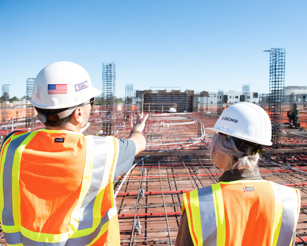 Two site engineers in hard hats checking progress on a construction site