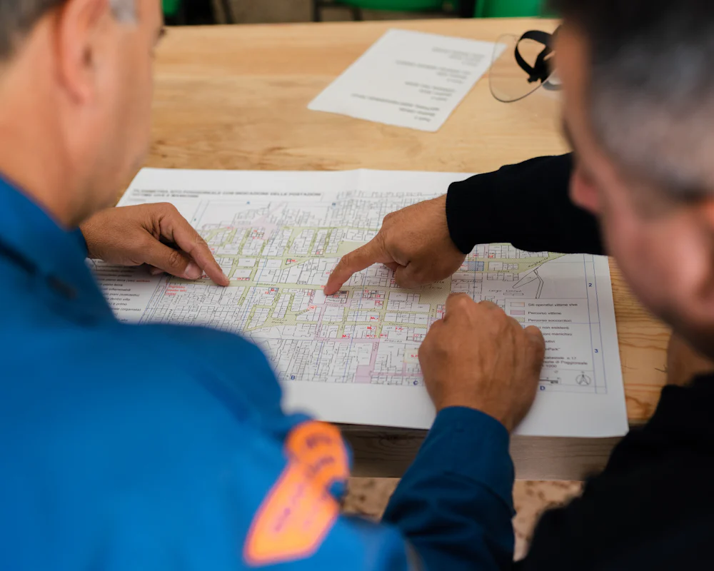 Two engineers reviewing printed project plans on a table