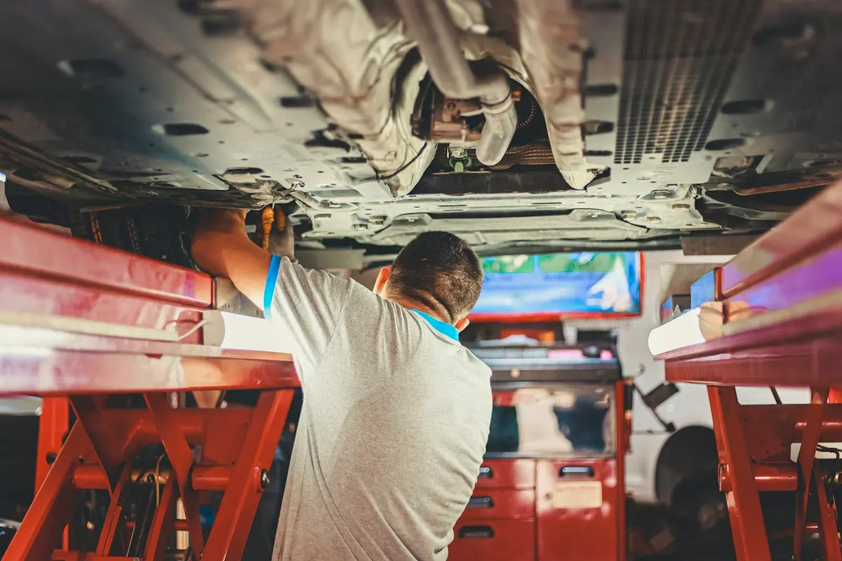 Mechanic working under a car raised on a workshop lift