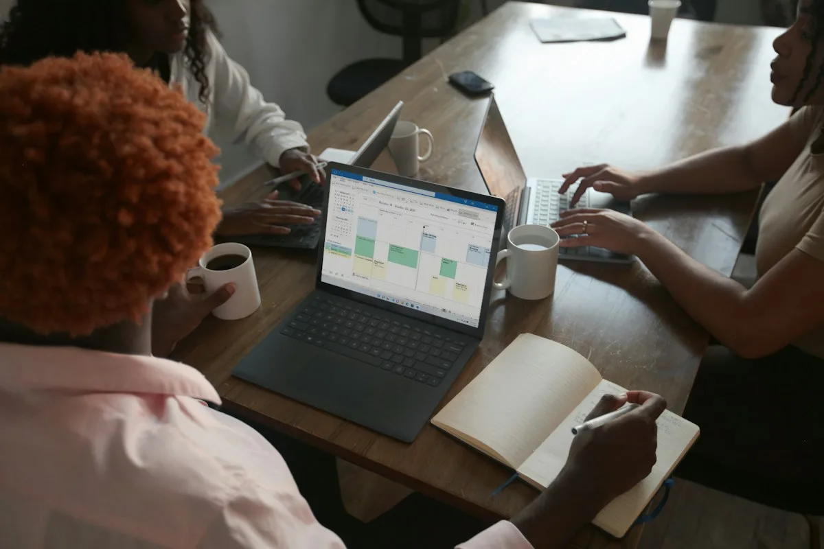 Three colleagues reviewing figures on a laptop in a meeting
