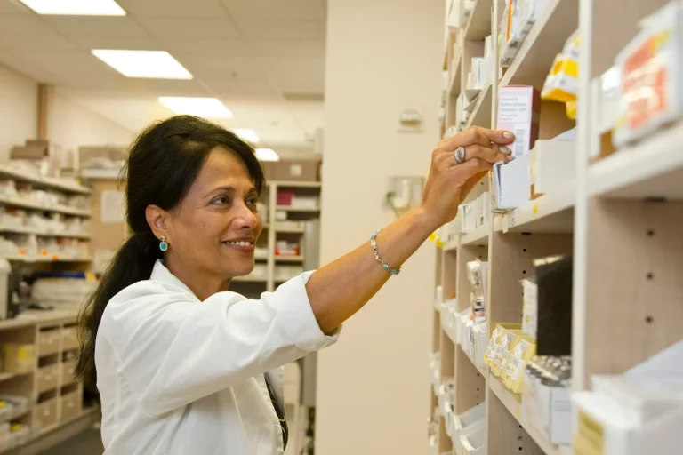 Pharmacist selecting a medicine box from the pharmacy stock shelves
