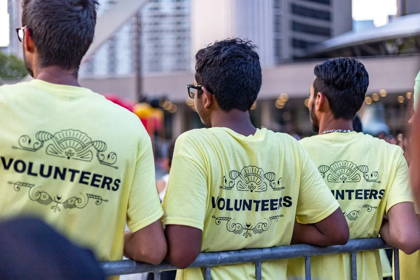 Three volunteers in matching shirts seen from behind at a community event