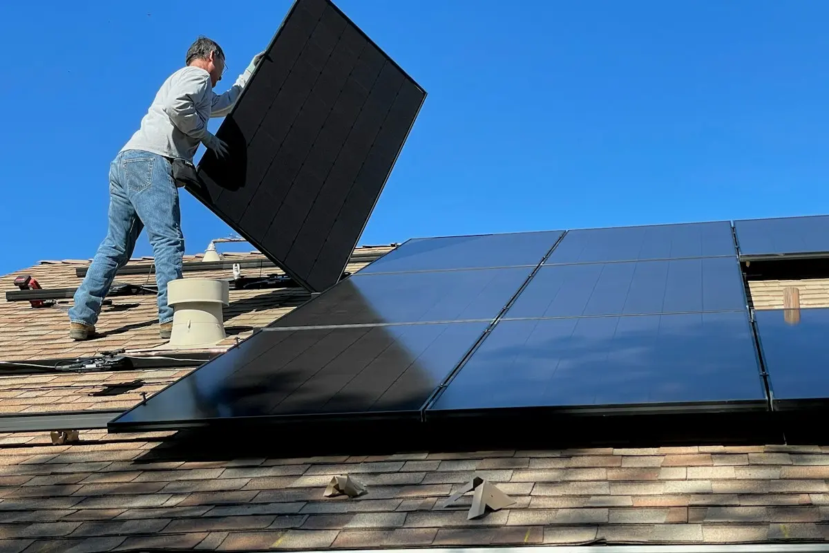 Installer carrying a solar panel across a roof